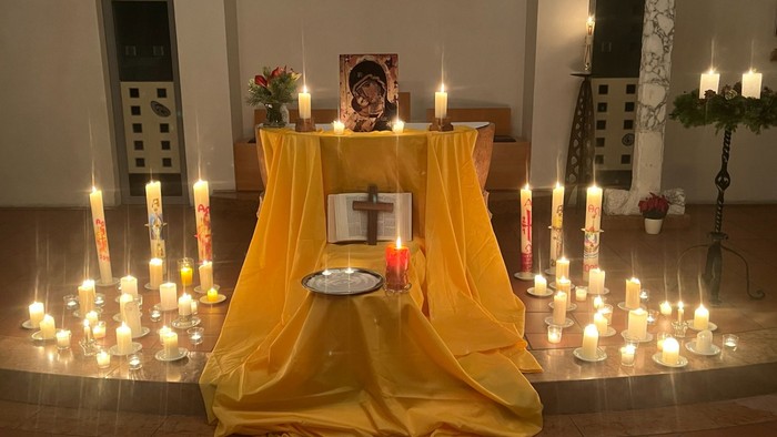 Kerzen auf dem Boden, Maria mitdem Kind und ein Kreuz auf einem Buch