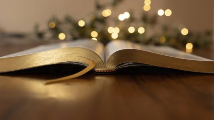 Offenes Buch liegt auf einem Holztisch vor Weihnachtsbeleuchtung