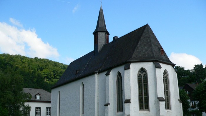 Weiße Kirche mit hohem Turm auf grünem Hügel