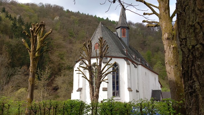 Kleine weiße Kirche mit schwarzem Dach in ländlicher Umgebung