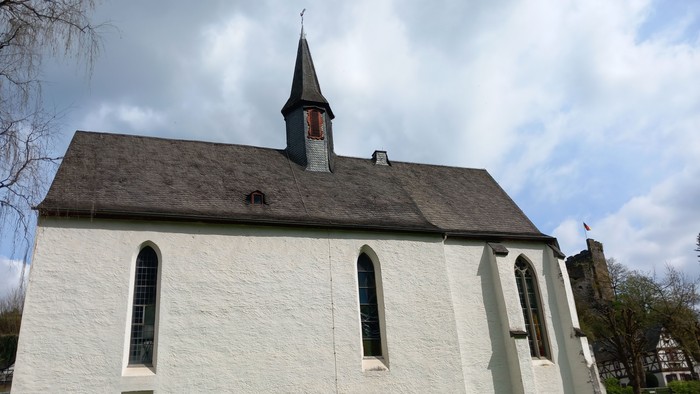 Weiße Kirche mit hohem Turm und Friedhof davor