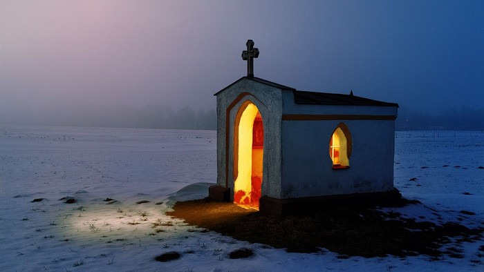 Kirche in Abenddämmerung und Schneelandschaft, Innenraum hell erleuchtet