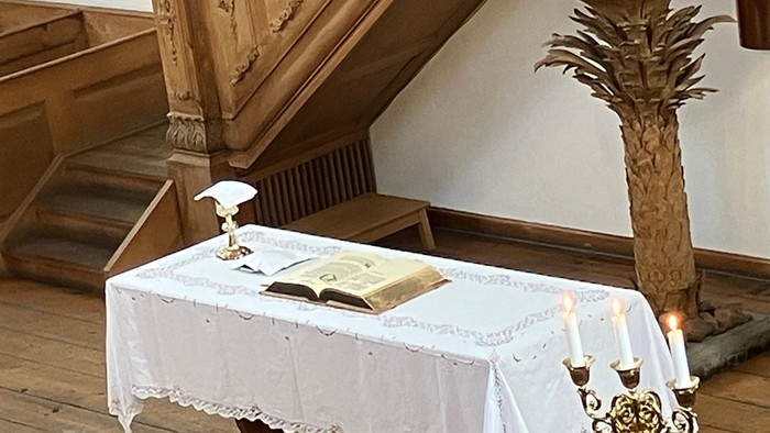 Eleganter Altartisch mit einem aufgeschlagenen Buch, Kerzen und verzierten religiösen Dekorationen in historischem Ambiente.