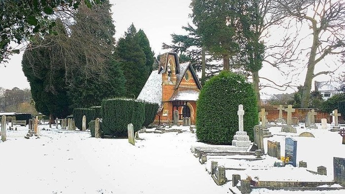Snow-covered cemetery with small chapel and gravestones