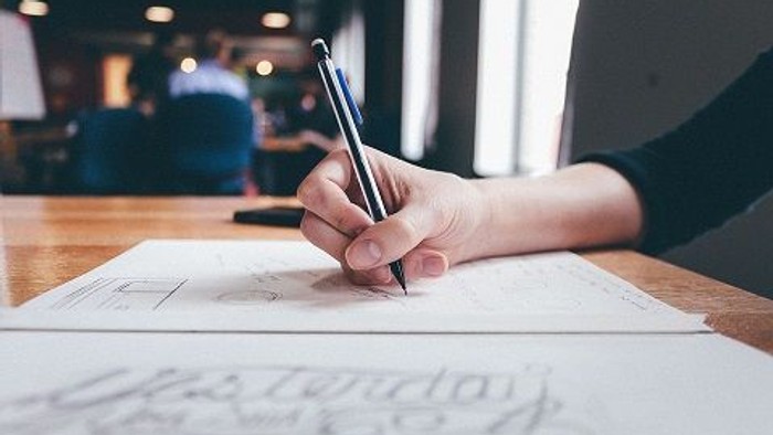 Hand schreibt mit Stift auf Papier