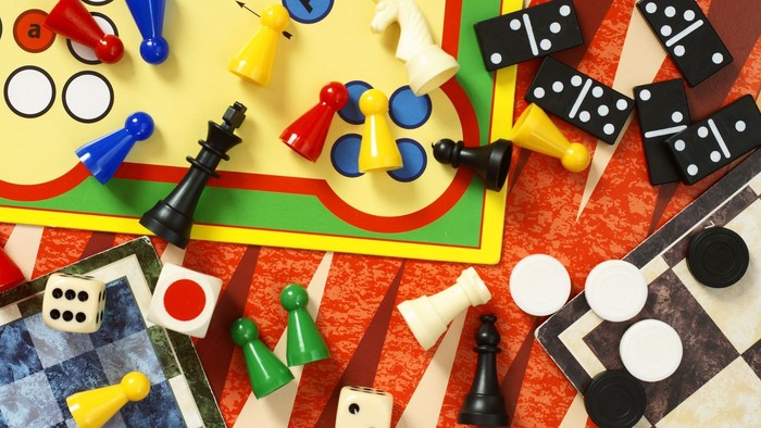 Bunte Auswahl an Brettspielsteinen, darunter Dominosteine, Schachfiguren und Lego-ähnliche Spielmarken.