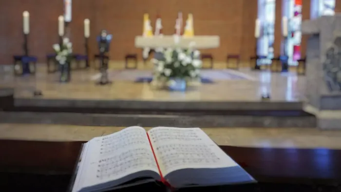 Offene Lobbuch auf Kirchenaltar mit Kerzen und Blumen