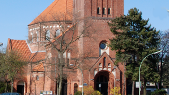 Große rote Backsteinkirche mit hohem Turm und spitzem Dach.