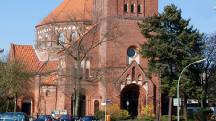Große rote Backsteinkirche mit hohem Turm und spitzem Dach.
