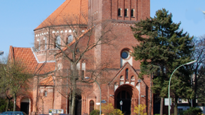 Große rote Backsteinkirche mit hohem Turm und spitzem Dach.