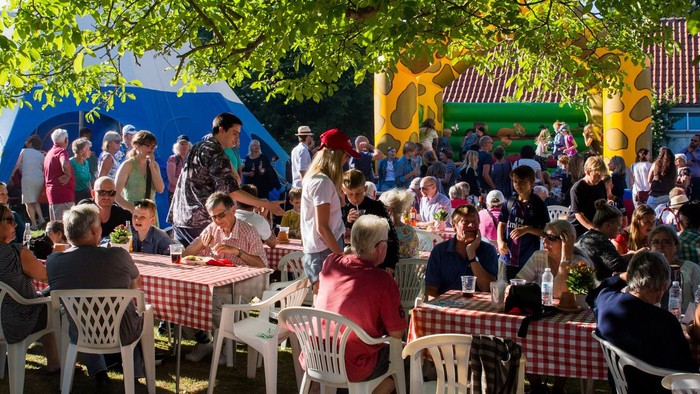 En folkelig fest med mange mennesker, der sidder ved bord og spiser.
