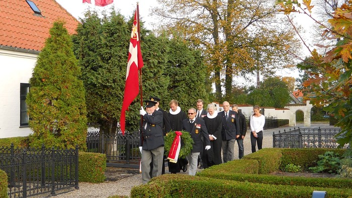 En gruppe personer står ved en mur med en dansk flag.