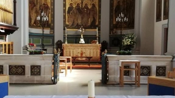 Church interior with altar, religious art, and candle.