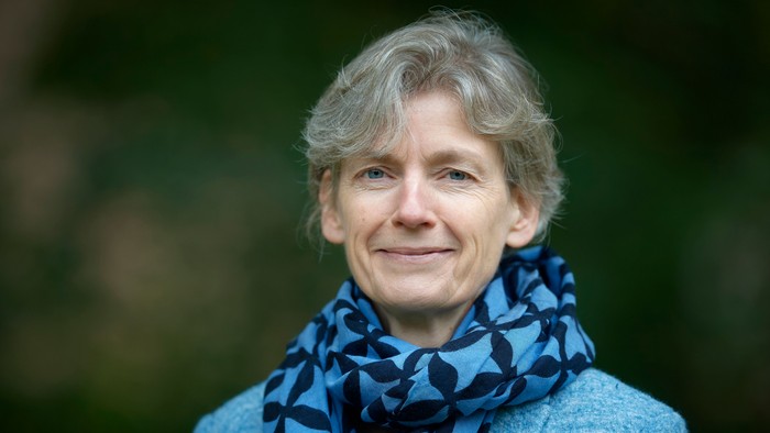 En kvinde med kort hår og blå skjorte med mønster.