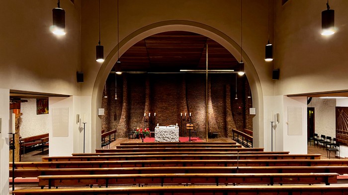 Die Kirche mit hölzernen Bänken und einem Altar im Vordergrund