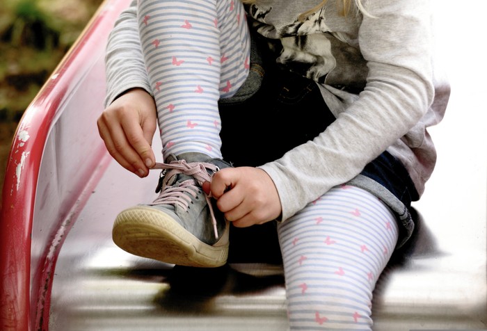 Kind auf Rutsche bindet sich Schuhe