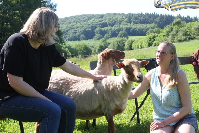Streicheleinheiten für die tierischen Protagonisten durften beim Treffen des Arbeitskreises für religionspädagogisches Arbeiten auf der Schafswiese in Herzhausen nicht fehlen. Kerstin Vollmerhausen und Maria Ronzheimer ließen sich nicht lange bitten. (Foto: Klaus Kordesch /eöa)