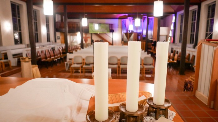 Eine Menschenmenge bei trüben Wetter vor einer hell erleuchteten Kirche.