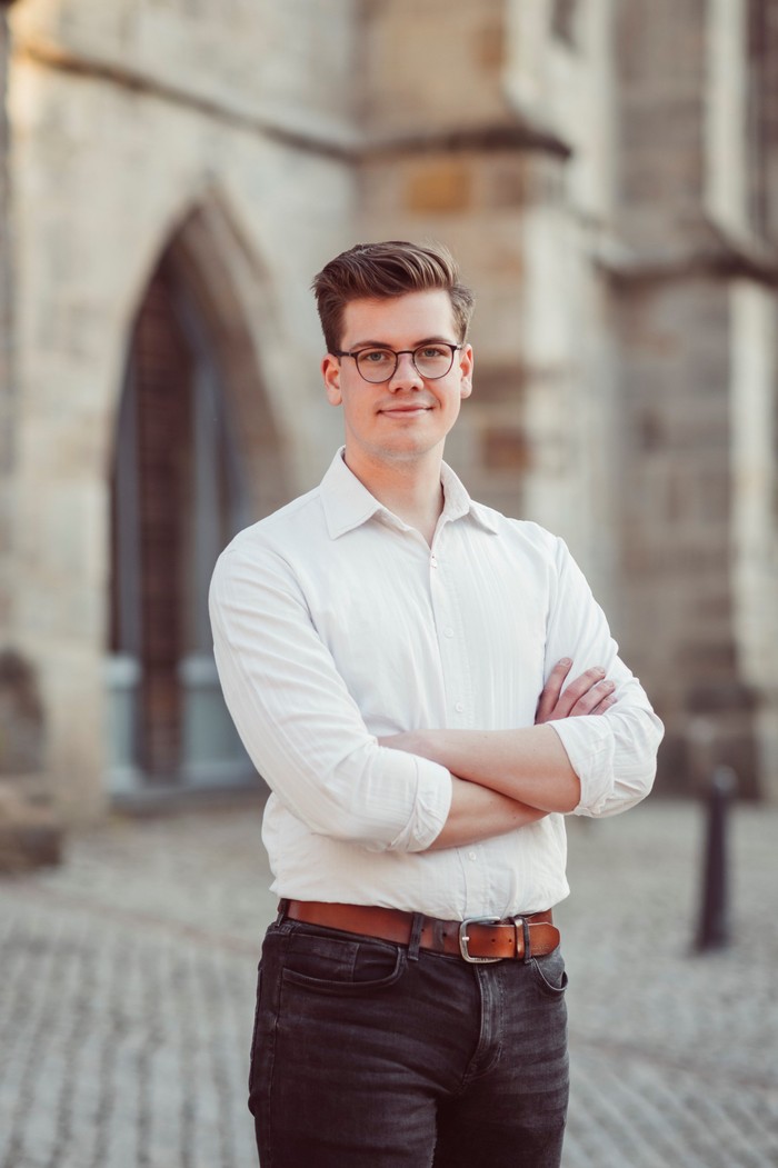 Das Foto zeigt Kantor Jan-Christoph Weige vor der Stadtkirche St. Anna Wolfhagen.