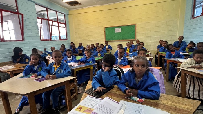 Klassenzimmer voller Schüler in Uniformen, die aufmerksam an ihren Pulten arbeiten.