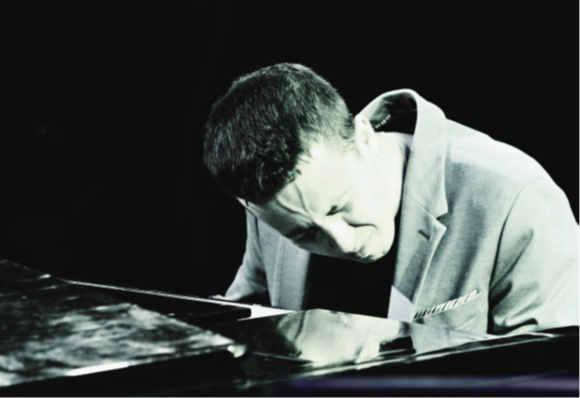 Ein konzentrierter Pianist, der intensiv auf einem Flügel in einem schwach beleuchteten Raum spielt.