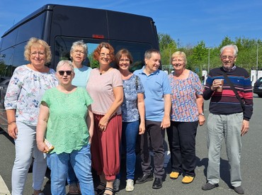 Eine Gruppe lächelnder Menschen vor einem Kleinbus. Eine Gruppe lächelnder Menschen vor einem Kleinbus.