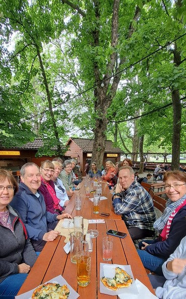 Menschen essen fröhlich an einem Holztisch unter Bäumen. Menschen essen fröhlich an einem Holztisch unter Bäumen.
