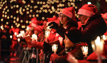 Singende Kinder und Erwachsene mit leuchtenden Kerzenständern