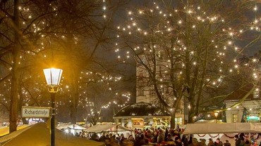 Abendlicher Weihnachtsmarkt unter beleuchteten Bäumen