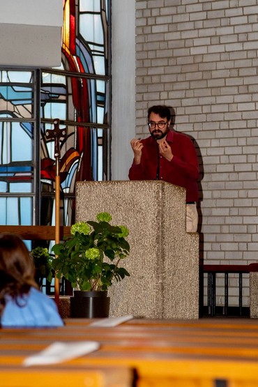 Eine Person steht am Ambo in einer Kirche und spricht.
