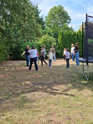 Die Kindergruppe mit Team und Familien beim Spielen im Garten.