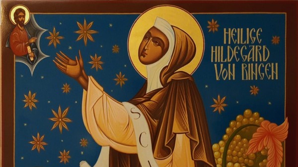 Heilige Hildegard von Bingen, dargestellt in einem himmlischen, goldenen Gewand mit ausgebreiteten Armen und einem Heiligenschein.