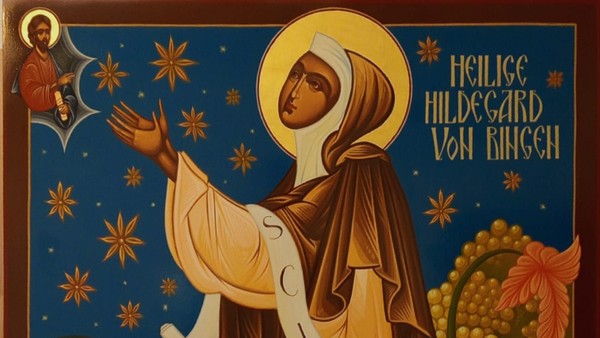 Heilige Hildegard von Bingen, dargestellt in einem himmlischen, goldenen Gewand mit ausgebreiteten Armen und einem Heiligenschein.